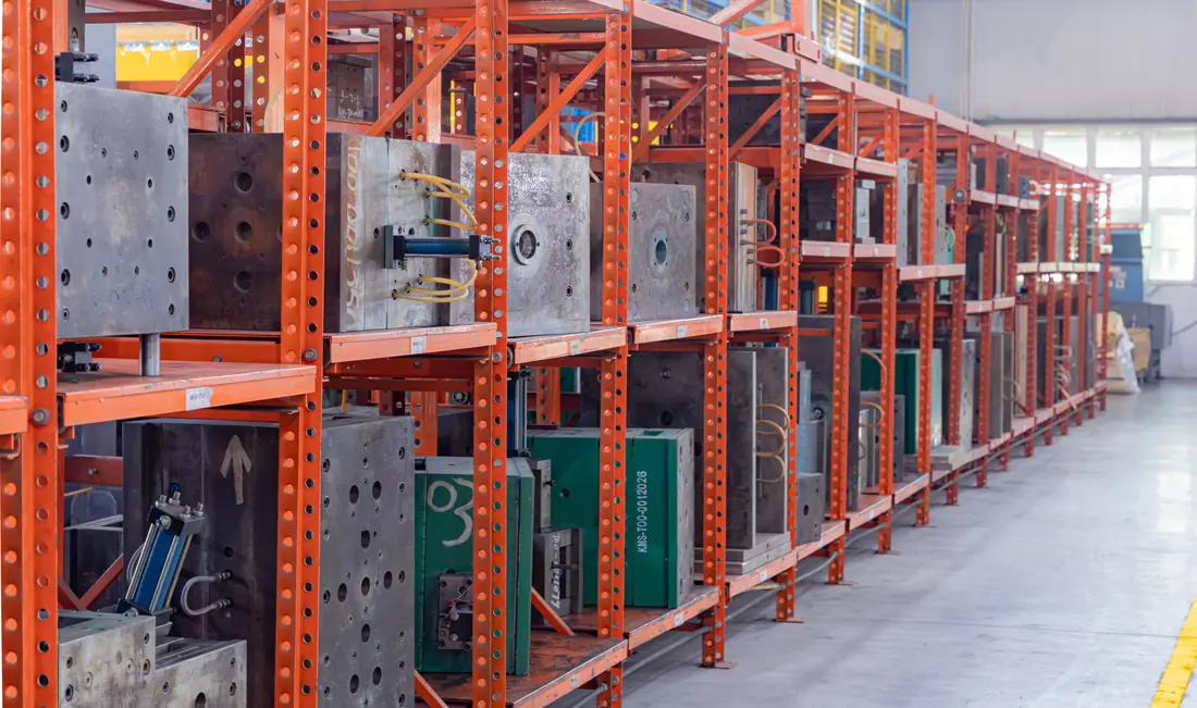 Rows of injection molds stored on steel racks at Komaspec