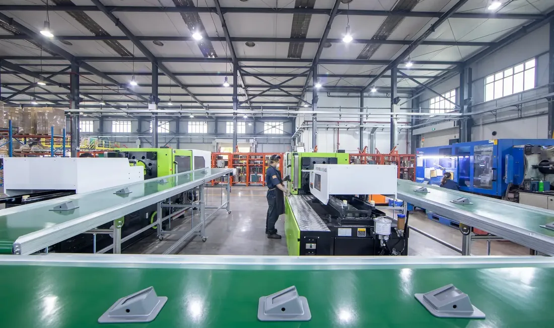 Technician operating a Yizumi injection molding press on the production floor